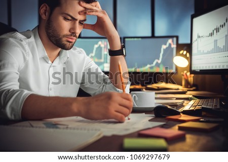 Serious businessman thinking hard of problem solution working late in office with computers documents, thoughtful trader focused on stock trading data analysis, analyzing forecasting financial rates