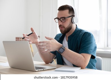 Serious businessman wearing headphones using laptop, speaking, making video call, confident young man intern worker looking at computer screen and talking, manager consulting client customer online - Shutterstock ID 1817935958