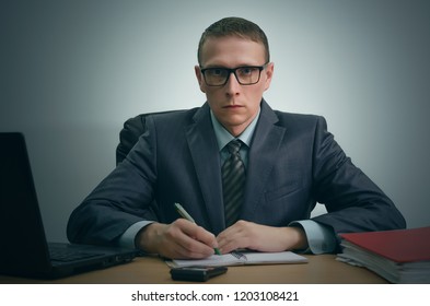 Serious businessman is working with documents and is sitting by the table.