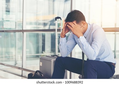Serious businessman worrying something, sitting and touch his head at the airport terminal. Businessman miss his flight. Young man feeling sick before business trip.