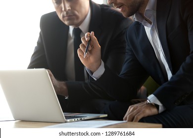 Serious businessmen in suits talk work together with laptop, financial advisor consulting convincing client about online investment benefits concept, make business offer with computer, close up view