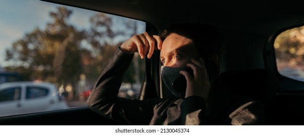 Serious Businesswoman With Protective Face Mask Talking On Mobile Phone From The Backseat Of The Car, Selective Focus