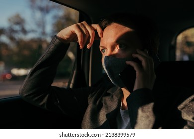 Serious Businesswoman With Protective Face Mask Talking On Mobile Phone From The Backseat Of The Car, Selective Focus