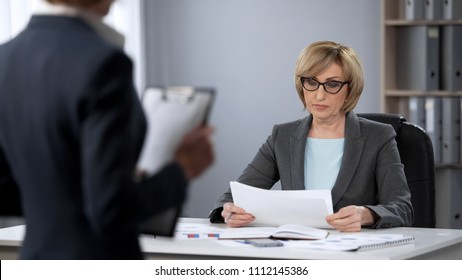 Serious businesswoman strictly looking at secretary, poor performance, bad work