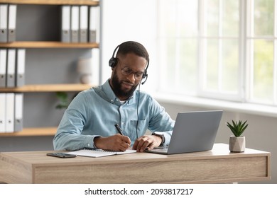 Serious busy millennial african american bearded guy manager in glasses, headphones work or study with laptop in office home interior. Modern distance work and business at home due covid-19 pandemic - Powered by Shutterstock