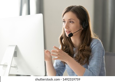 Serious call center operator in wireless headset talking with customer, woman in headphones with microphone consulting client on phone in customer support service, looking at computer screen close up - Shutterstock ID 1492319759
