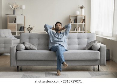 Serious calm young Indian man resting on home couch, sleeping, enjoying leisure time, silent peaceful break, pause, relaxing, sitting on comfortable sofa in modern cozy apartment - Powered by Shutterstock