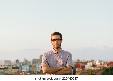 Serious Casual Man With Smart Geek Looking Standing Against City Background Crossing Arms.