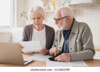 Serious caucasian old elderly senior couple grandparents family counting funds on calculator, doing paperwork, savings, paying domestic bills, mortgage loan, pension at home using laptop.