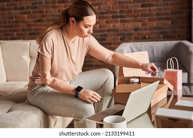 Serious Caucasian Woman With Artificial Limb Sitting At The Table With Modern Laptop