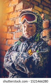 Serious Child In Military Uniform. Disappointed Kid With Crossing Arms. Disillusioned Young Stalker In Abandoned Building. Girl With Offended Facial Expression. Young Soldier Concept