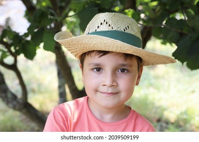 ernsthaftes Kind mit Strohhut auf dem Feld