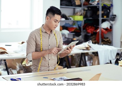 Serious clothing manufacture worker checking out new patterns on tablet computer