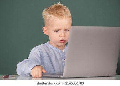 Serious Concentrate Child Using Laptop Computer, Kid Boy Studying Through Online E-learning. Little Funny System Administrator. Cute Pupil Face Closeup On Blackboard Background.