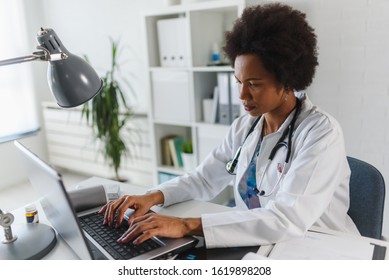 Serious concentrated African American doctor working in her office at clinic - Powered by Shutterstock