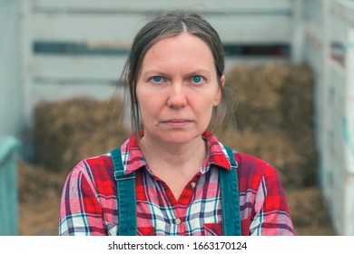 Serious Concerned Female Farmer Posing On Farm. Confident Woman Farm Worker Wearing Plaid Shirt And Jeans Overalls Looking At Camera.