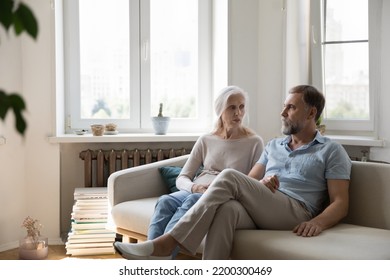 Serious concerned senior couple talking on home couch, having relationship problems, discussing bad news. Mature older wife asking offended husband for forgiveness. Marriage crisis - Shutterstock ID 2200300469