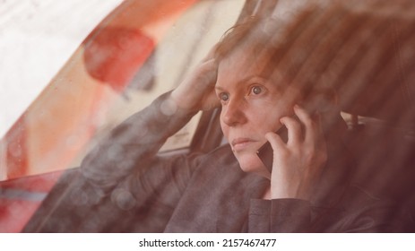 Serious concerned woman talking on mobile phone from the car, selective focus