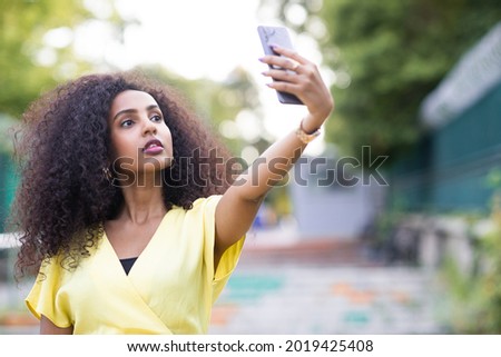 Similar – Frau mit Afro-Haaren auf der Straße, die ein Smartphone hält.