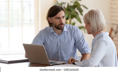 Serious Confident Businessman Talking To Middle Aged Female Partner. Mature Financial Advisor Consulting Focused Client At Office. Colleagues Discussing Project Retails, Sitting Together At Workplace.