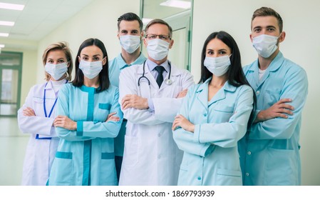 Serious confident doctors team in safety medical masks with crossed arms are looking on the camera on hospital background - Shutterstock ID 1869793939