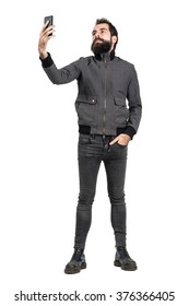 Serious Confident Hipster Or Punker Taking Selfie Self Portrait With Mobile Phone. Full Body Length Portrait Isolated Over White Studio Background. 