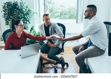 Serious confident male employee showing online document on phone to colleague explaining his plan. Handsome Hispanic male manager passing device to business lady. Collaboration concept - Powered by Shutterstock