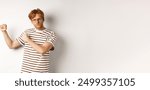 Serious and confident redhead man in glasses raising fists, ready for fight, staring angry at camera while shadow boxing, standing over white background.