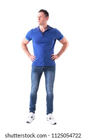 Serious Confident Young Adult Casual Man In Blue Polo Shirt Looking Away With Arms On Hips. Full Body Isolated On White Background.