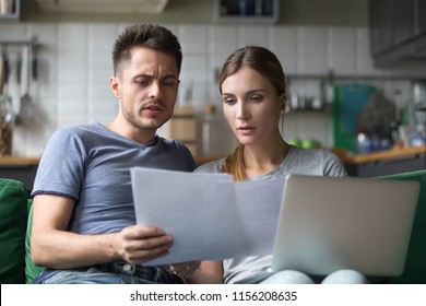 Serious confused couple checking high domestic bills with papers and laptop, millennial family discussing expenses or financial problems bankruptcy debt loan reading bad news in bank documents