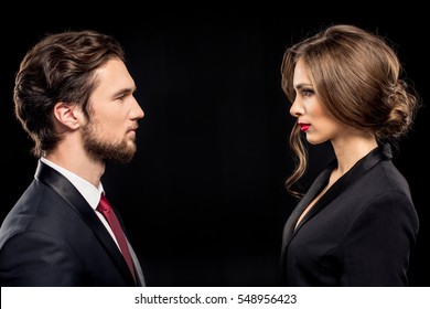 Serious Couple In Formal Wear Looking At Each Other Isolated On Black