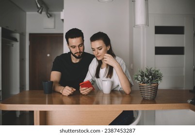 Serious couple with smartphone hugging in modern apartment - Powered by Shutterstock