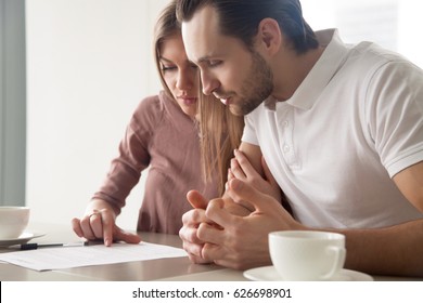 Serious couple studying contract agreement, reading terms and conditions attentively before signing, husband and wife calculating domestic bills, considering mortgage loan offer, health insurance  - Powered by Shutterstock