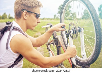 Serious cyclist man checks wheel of bicycle in summer park, repair of bicycle - Powered by Shutterstock