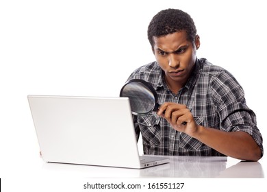 serious dark-skinned man concentrated looking through a magnifying glass on his laptop