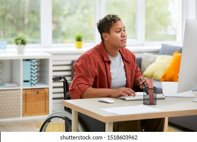 Serious disabled woman concentrating on her work she sitting at her workplace and working on computer at office