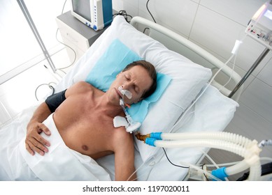 Serious Disease. Top View Portrait Of Male Patient On Mechanical Ventilator Resting In Recovery Room