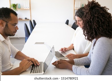 Serious diverse business colleagues meeting and working on project. Man and women in casual sitting at table, using laptops and talking. Workgroup concept - Shutterstock ID 1514780921