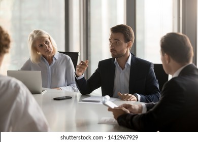 Serious Diverse Colleagues Brainstorm At Conference Table Discuss Project At Meeting, Focused Businesspeople Talk Negotiating In Office At Briefing, Business Partners Speak Considering Cooperation