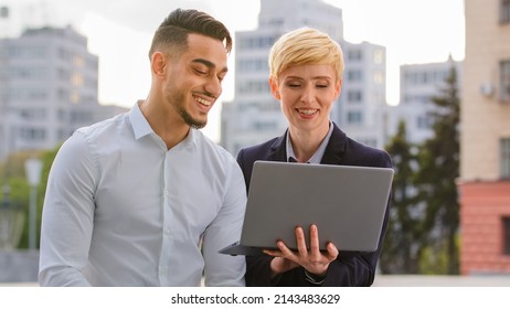 Serious Diverse Multiracial Couple Colleagues Arabic Hispanic Man And Caucasian Woman Standing Near Business Center At Street Looking At Computer Screen Laptop Discuss Project Analyze Data Teamwork