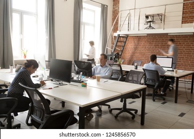 Serious diversity team of focused employees working online project in modern office space, using computers, teamwork, routine work day, busy office workers at workplace, white mock up monitor