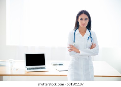 Serious Doctor With Crossed Hands Standing Near The Window