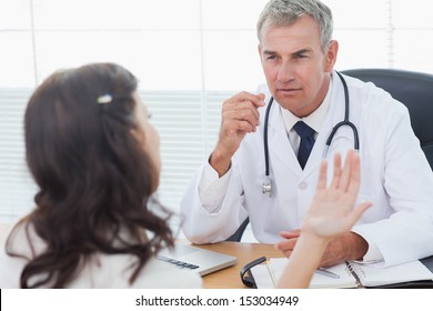 Serious Doctor Listening To His Patient Talking In Bright Surgery