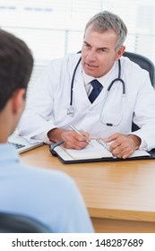 Serious Doctor Prescribing Drug To His Patient In Bright Surgery