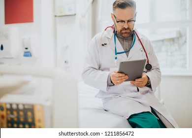 Serious Doctor Reading From A Tablet