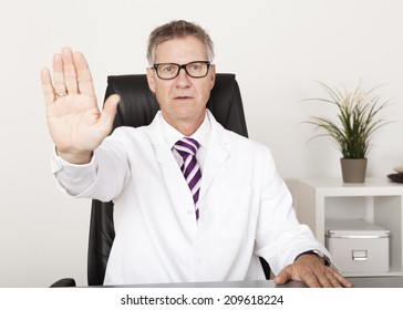 Serious Doctor Showing Hand Stop Sign While Sitting On Chair