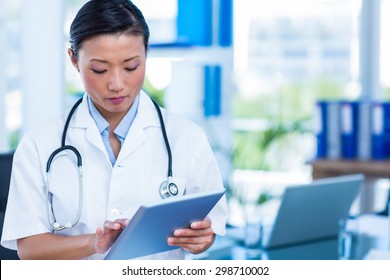 Serious Doctor Using Tablet In Medical Office