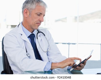 Serious Doctor Working With A Tablet Computer In His Office