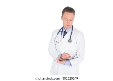 Serious Doctor Writing On A Clipboard Against A White Background