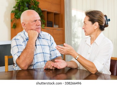 Serious Elderly Couple Talking In Home Interior